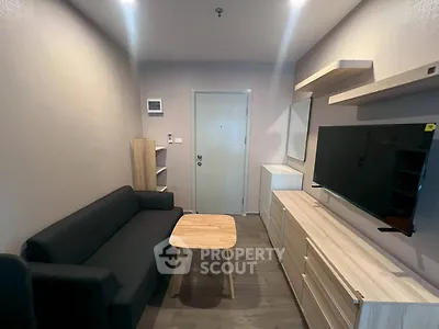 Modern living room with sleek furniture and wall-mounted TV in a cozy apartment.