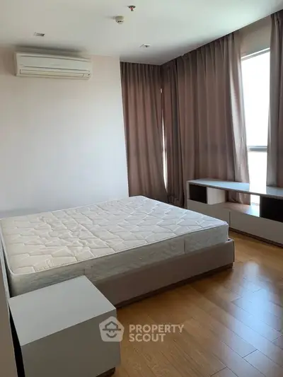 Spacious bedroom with natural light and modern furnishings in a stylish apartment.