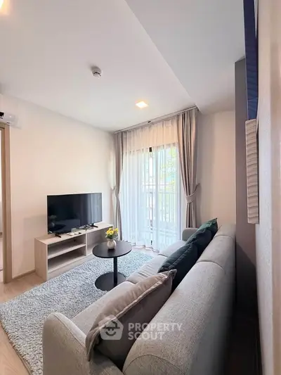 Modern living room with cozy sofa, TV, and natural light from large window.