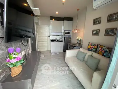 Modern living room with cozy sofa, wall-mounted TV, and compact kitchen area.