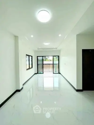 Spacious and bright living room with large windows and balcony access.