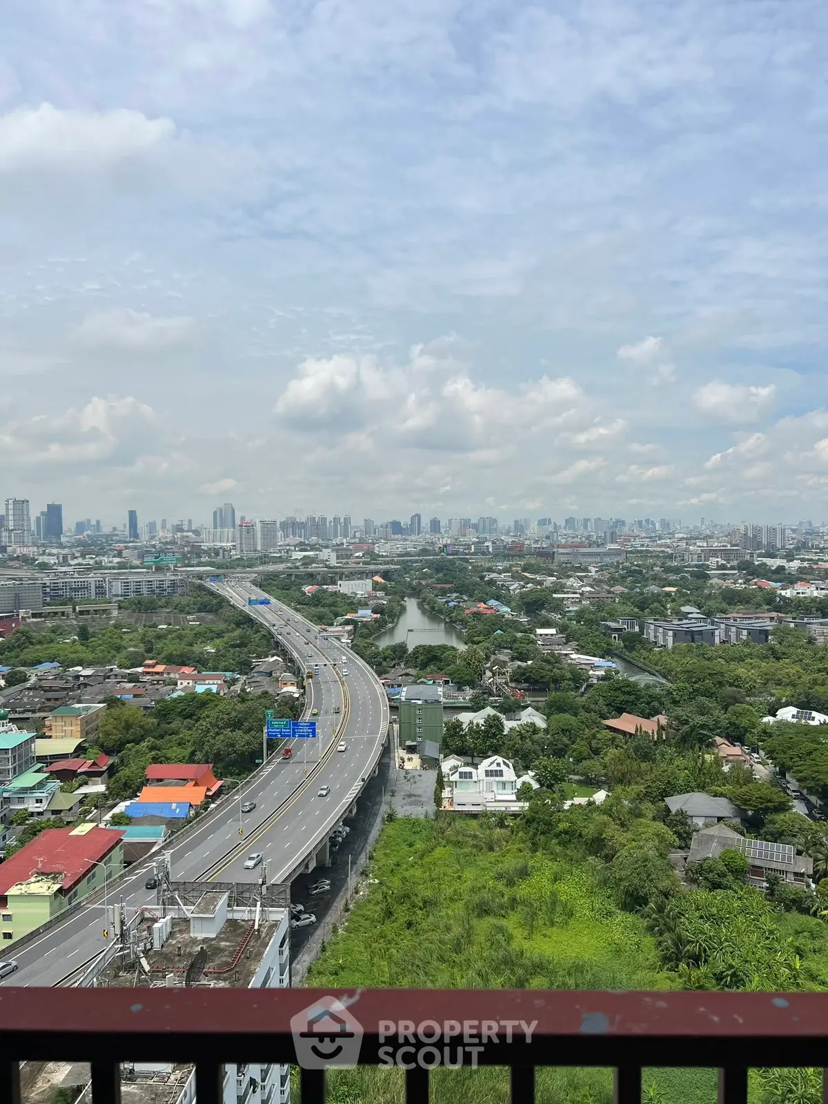 Stunning cityscape view from a high-rise balcony overlooking urban skyline and highway.