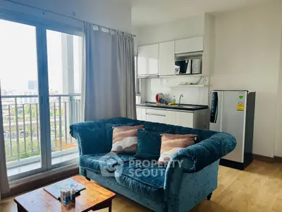 Modern living room with cozy sofa and compact kitchen, featuring a balcony with city view.
