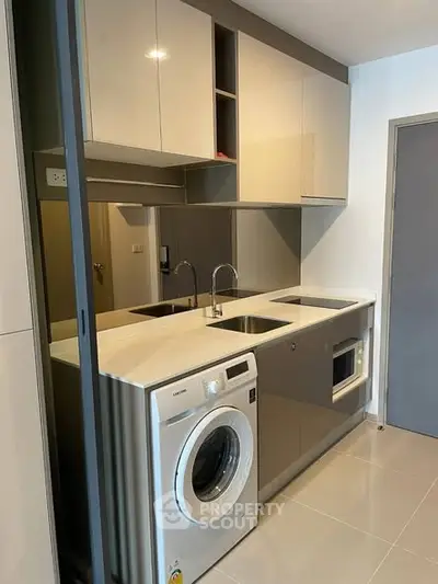 Modern kitchen with sleek cabinetry and built-in appliances, featuring a washing machine and microwave.
