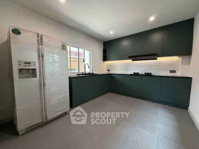 Modern kitchen with sleek dark cabinets and new appliances in a spacious layout.