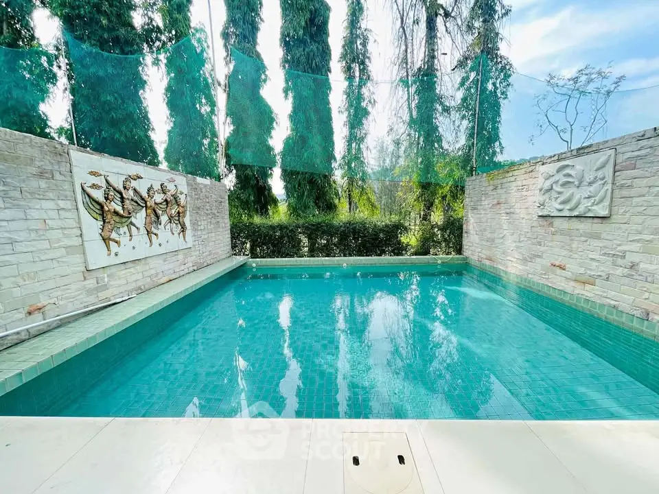 Luxurious private pool with artistic wall decor and lush greenery