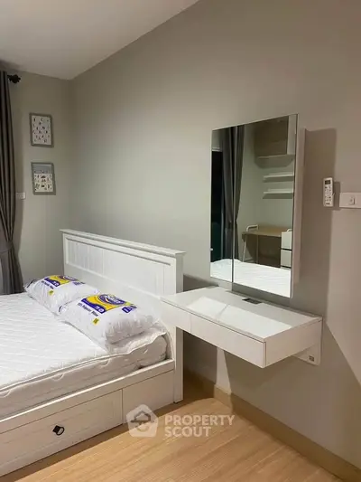 Modern bedroom with sleek white furniture and wall-mounted mirror, showcasing minimalist design and cozy ambiance.