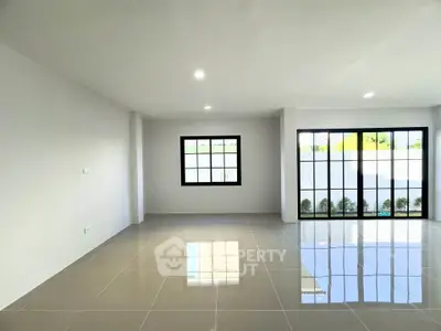 Spacious modern living room with large windows and glossy tiled floor, perfect for natural light lovers.