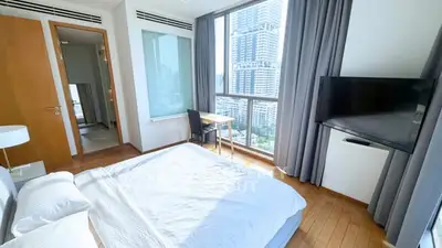 Bright and modern bedroom with city view, featuring a large window, wooden flooring, and a flat-screen TV.