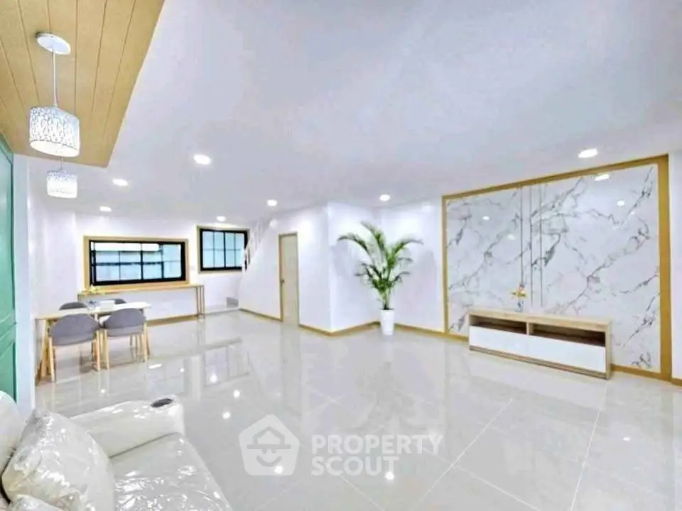 Spacious modern living room with elegant marble accents and open dining area.