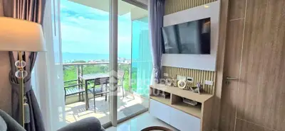 Modern living room with balcony and stunning ocean view, featuring a wall-mounted TV and stylish decor.