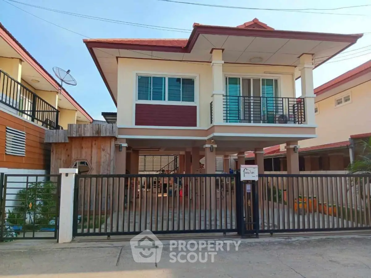 Charming two-story house with balcony and gated entrance in a serene neighborhood.