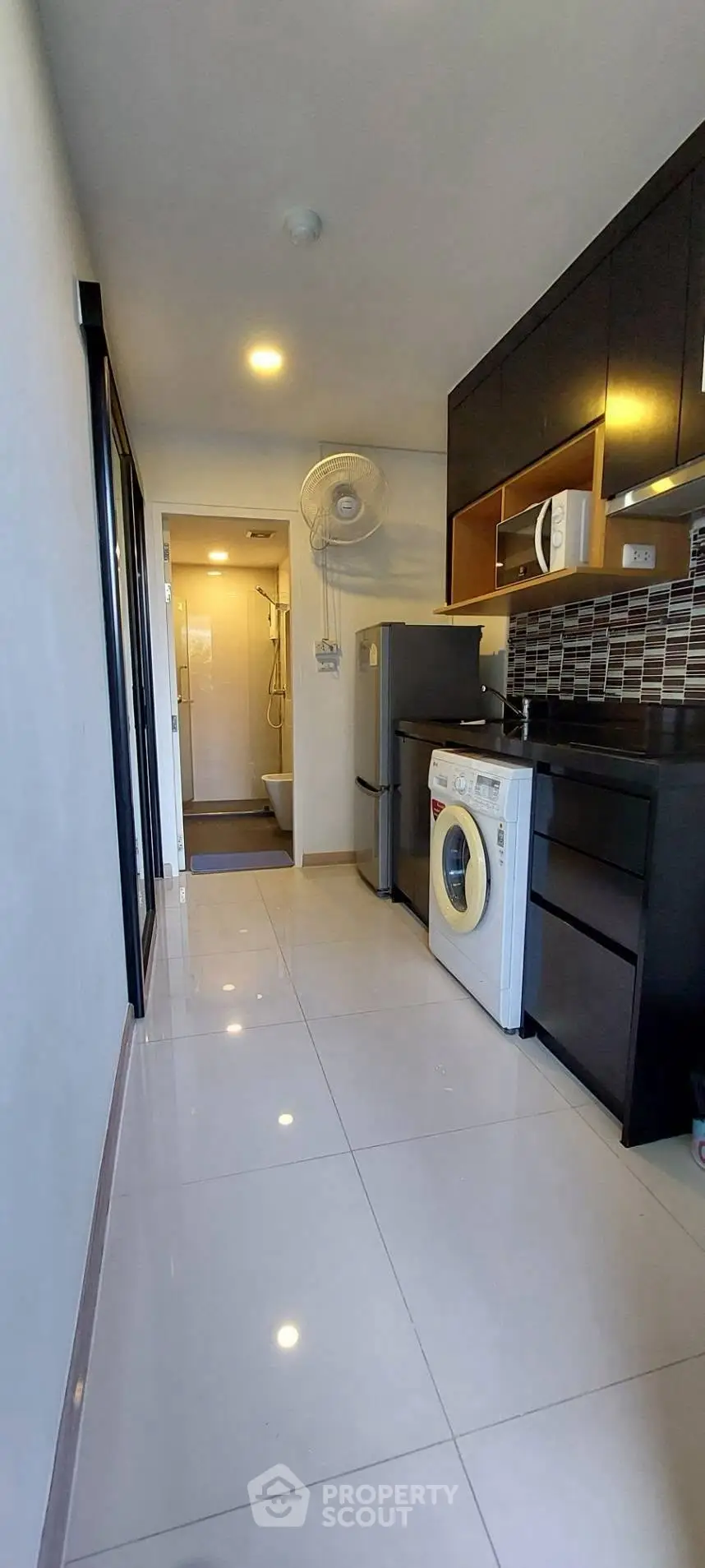 Modern kitchen with sleek appliances and glossy tiles in a compact layout