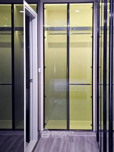 Modern walk-in closet with sleek glass doors and stylish interior design.