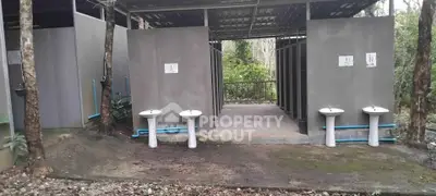 Outdoor public restroom facilities with sinks and forest surroundings.
