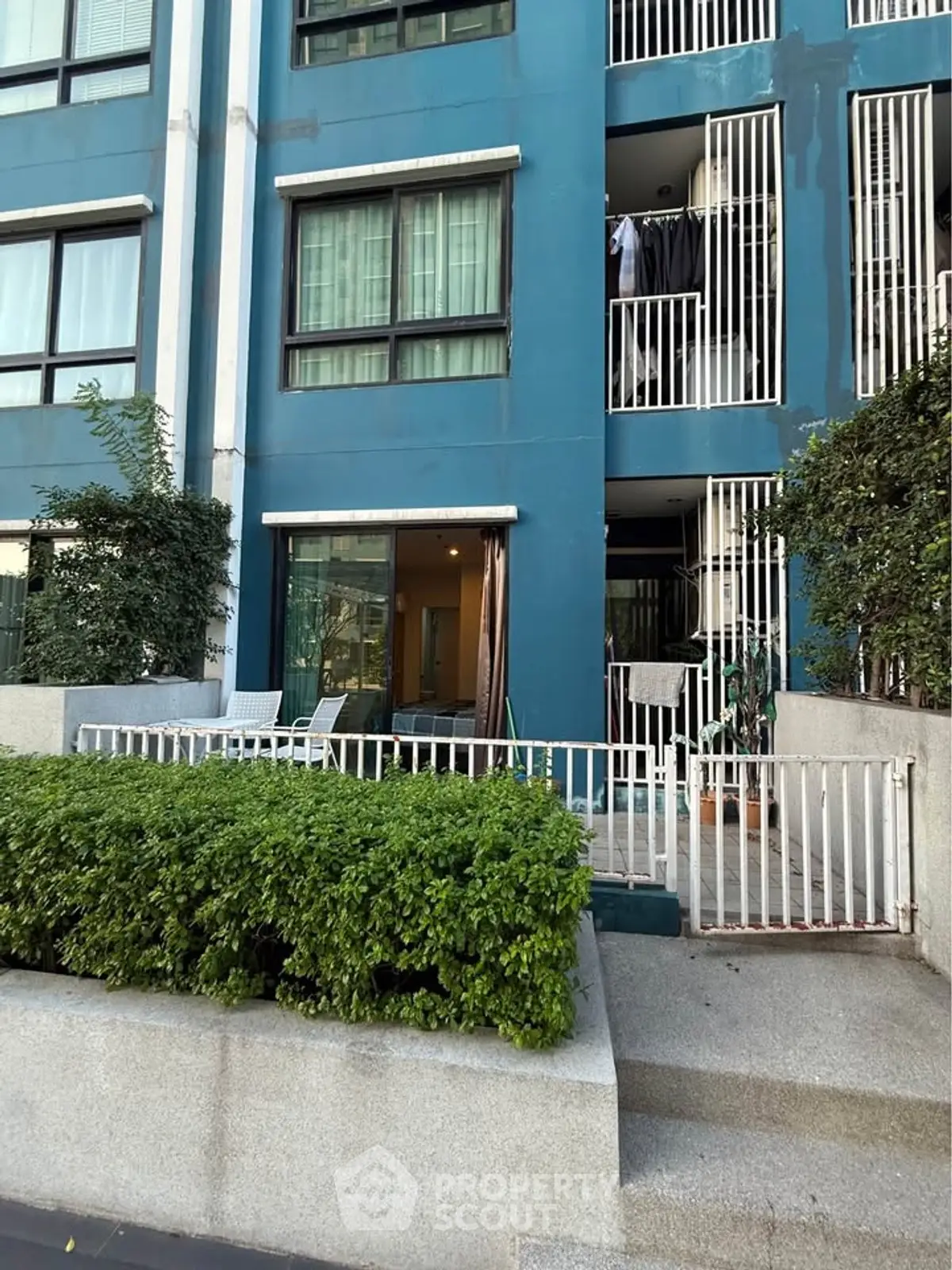 Modern apartment building exterior with lush greenery and private balconies.