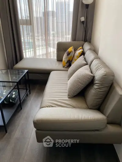 Modern living room with stylish leather sofa and city view through large windows.