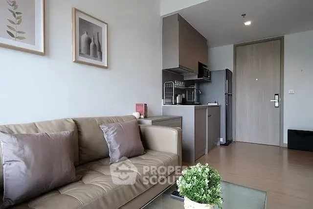Modern living room with cozy sofa and compact kitchen in open layout apartment.