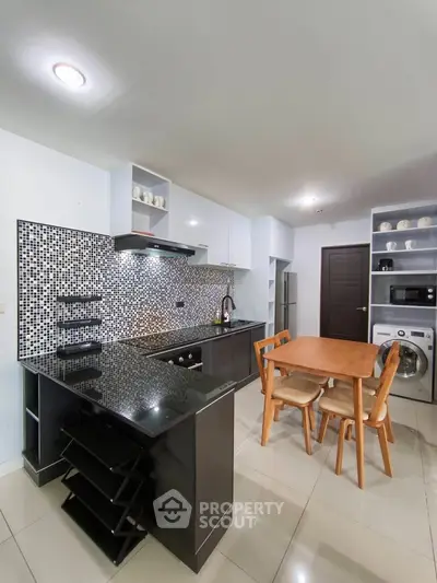 Modern kitchen with sleek black countertops and dining area in open layout