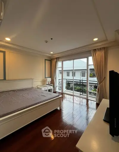 Spacious bedroom with elegant decor and large window offering natural light and garden view.