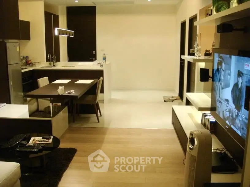 Modern open-layout living room with kitchen, featuring sleek furniture and ambient lighting.