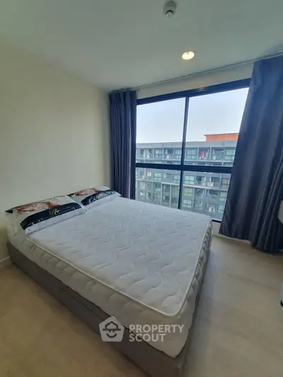 Modern bedroom with large window offering city view in high-rise apartment