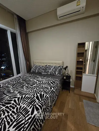 Cozy bedroom with city view, featuring modern decor and air conditioning.