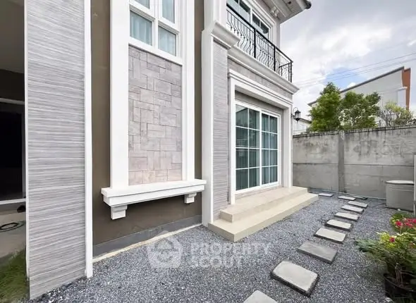 Elegant modern house exterior with stylish stone pathway and large windows.