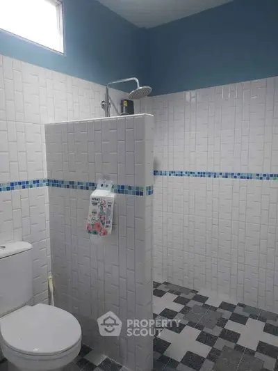 Modern bathroom with stylish white tiles and blue accents, featuring a sleek shower area and contemporary fixtures.