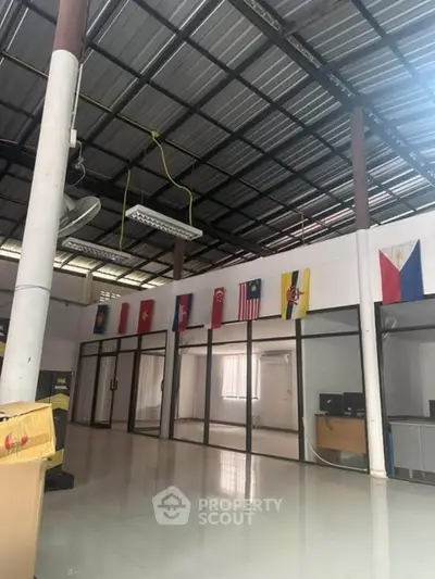 Spacious commercial interior with high ceiling and international flags, ideal for office or retail use.