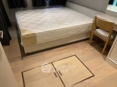 Cozy bedroom with wooden flooring and built-in storage under the bed, featuring a comfortable mattress and a wooden chair.