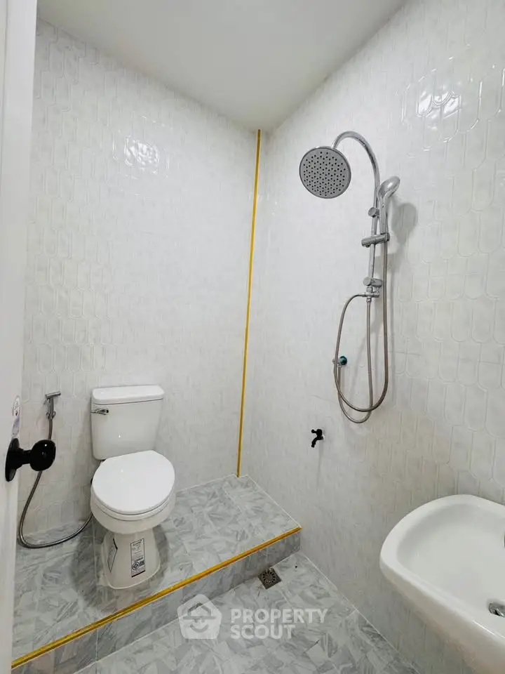 Modern minimalist bathroom with shower and toilet in sleek white tiles.