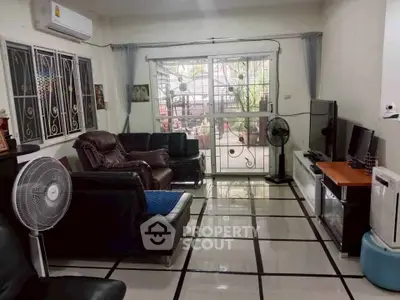 Spacious living room with modern furniture and large windows overlooking a garden patio.