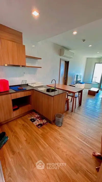 Modern open-layout kitchen with wooden flooring and sleek cabinetry in a bright apartment.