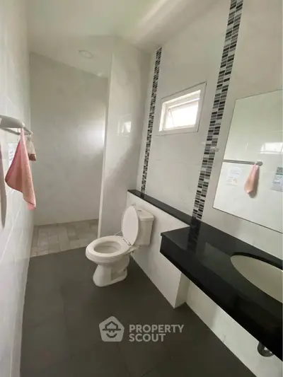 Modern bathroom with sleek black countertop and tiled shower area