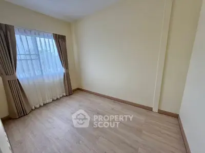 Spacious empty room with wooden flooring and large window, perfect for customization.