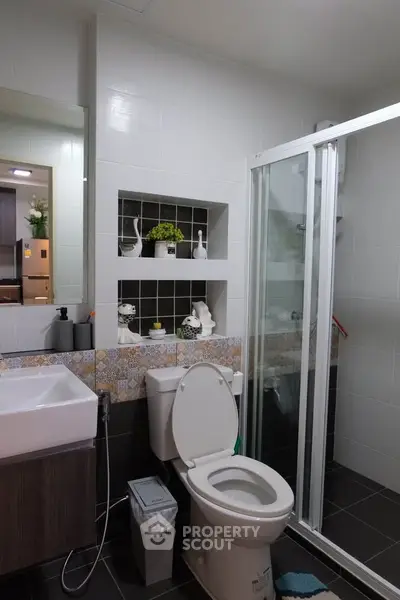 Modern bathroom with glass shower, stylish sink, and decorative shelving.