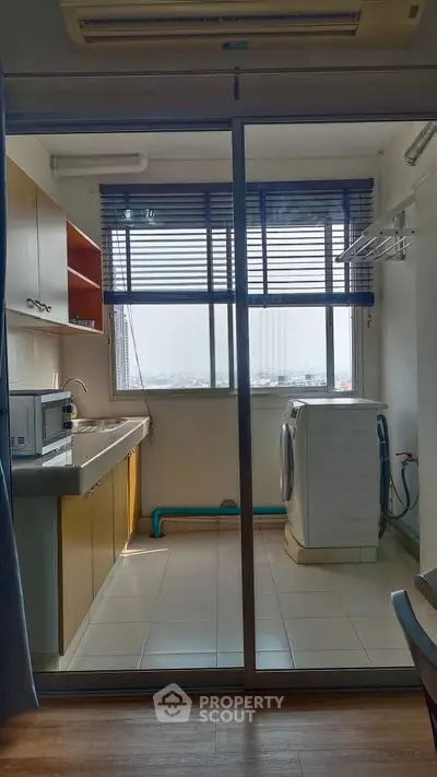 Bright kitchen with washing machine and large window in modern apartment