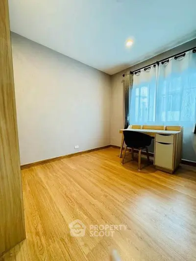 Spacious study room with wooden flooring and natural light, perfect for productivity.