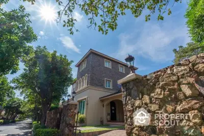 Charming stone facade house with lush garden and sunny sky