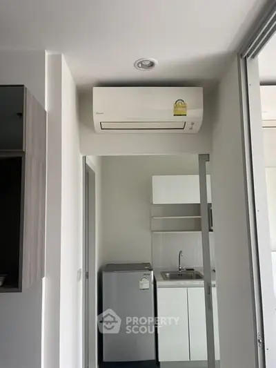 Compact kitchen area with modern appliances and air conditioning unit in a cozy apartment.