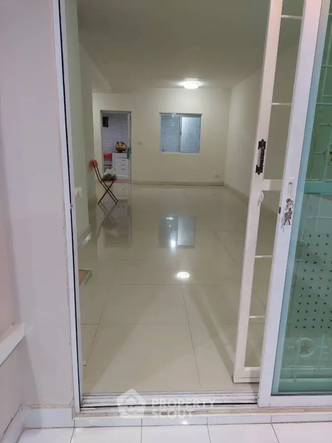 Spacious empty room with glossy tiled flooring and sliding glass doors