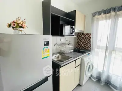 Modern kitchen with stainless steel appliances and washing machine in a bright apartment.