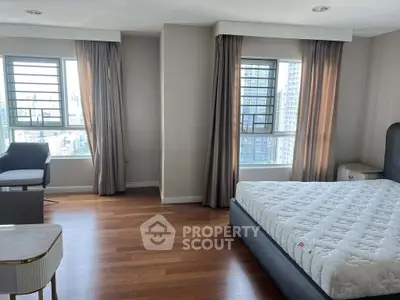 Spacious bedroom with city view, hardwood floors, and modern furnishings in a high-rise apartment.