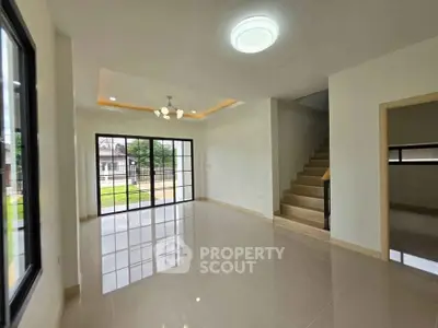 Spacious modern living room with large windows and staircase in elegant home