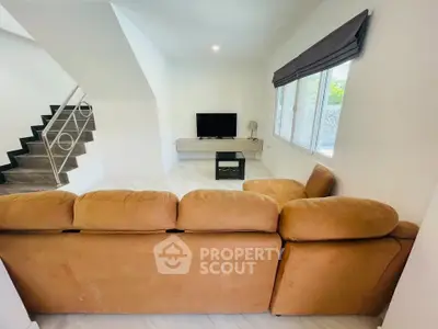 Spacious living room with cozy brown sofa and modern TV setup, perfect for relaxation.