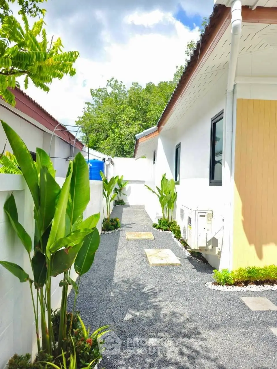 Charming exterior view of a modern home with lush greenery and a gravel pathway.