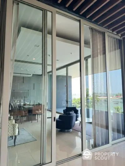 Luxurious modern living room with glass doors opening to a spacious balcony with stunning views.