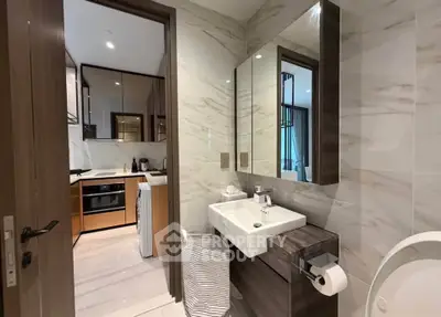 Modern bathroom with sleek fixtures and view into a stylish kitchen