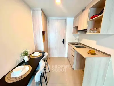 Modern kitchen with sleek cabinetry and dining area in a compact apartment setting.